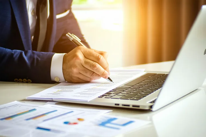 Financial analyst reviewing private credit deal documentation on a clean desk with printed reports